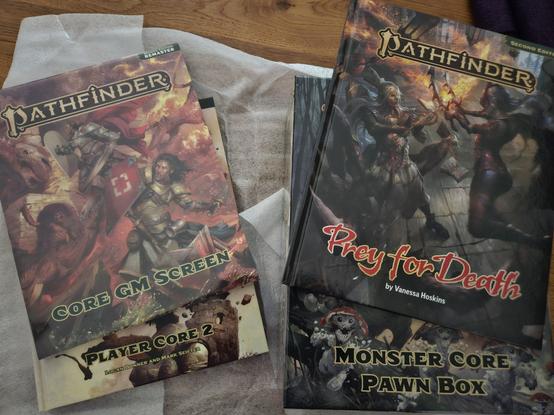 Neue Produkte für Pathfinder 2 auf einem Tisch: Player Core 2, Core GM Screen, Monstee Core Pawn Box und das Abenteuer "Prey for Death".