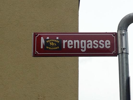 Ein Straßenschild mit einem rassistischen Straßennamen, den man wegen einem Sticker nicht mehr lesen kann.