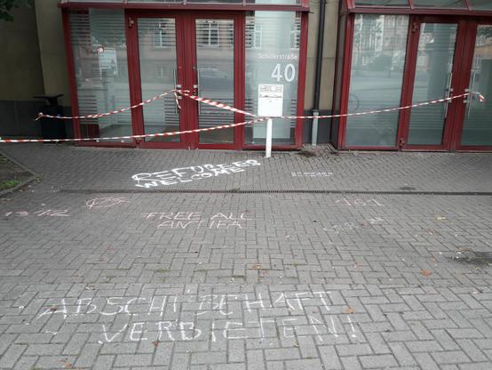 Die Ausländerbehörde, mit Sperrband abgesperrt. Auf dem Boden steht "Refugees Welcome" und "Abschiebehaft verbieten".