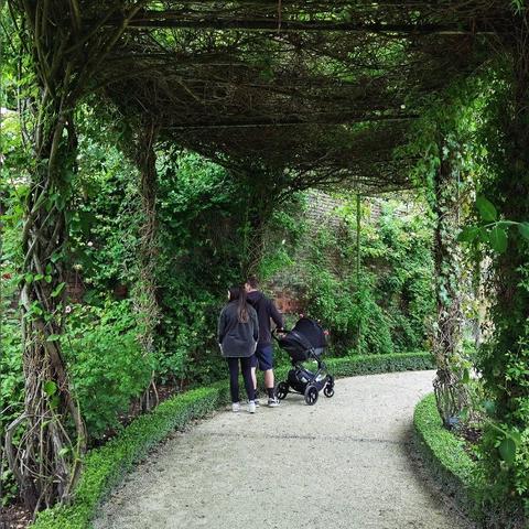 Couple with a pram looking at plants  from a enclosed path in Alnwick Gardens. | paar met kinderwagen kijkend naar planten vanaf een overdekt pad in de tuinen van Alnwick.