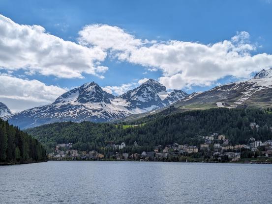 Panorama of Sankt Moritz, through the lake. It's a chilly summer day, about 16 degrees and windy, there's still a lot of snow on the mountains in the background.