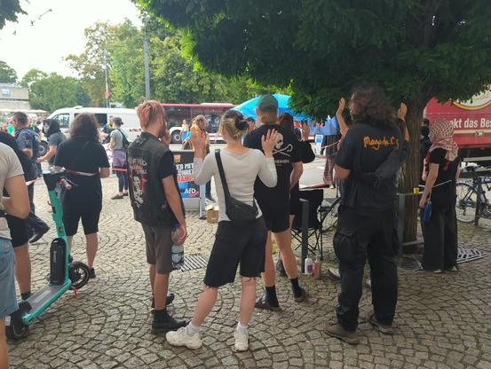 Antifaschist*innen stehen um einen AfD-Stand herum, der mit Flatterband und Bannern abgesperrt wurde.