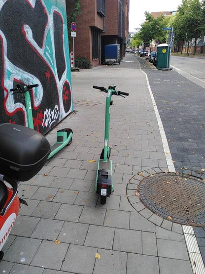 Ein Elektroroller direkt und behindernd auf dem Gehweg