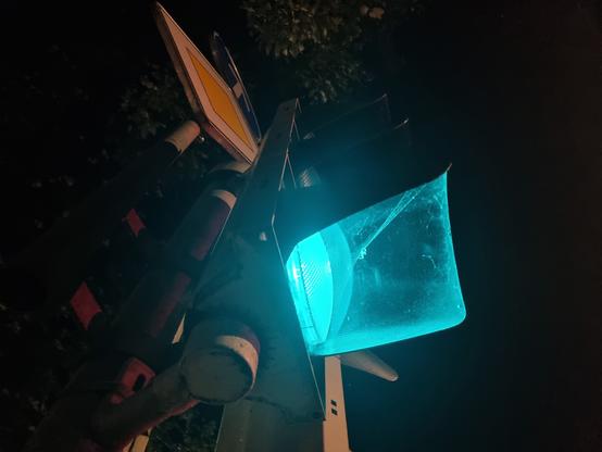 Grün leuchtende Ampel in dunkler Umgebung, von unten aufgenommen
