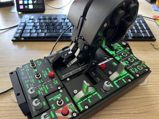 Flugsimulator-Drosselklappensteuerung auf einem Schreibtisch mit einer Tastatur und anderen Computergeräten im Hintergrund.