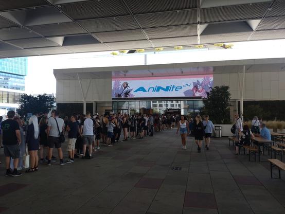 Viele Menschen, teilweise kostümiert, stehen Schlange vor dem Haupteingang zur Messe Wien (Austria Center). Ein riesiges Display über dem Haupteingang zeigt das Aninite Logo.