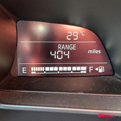 The dashboard display of a car showing that the current range is 404 miles. You can also see that the temperature is 29 Celsius and the parking brake is on.