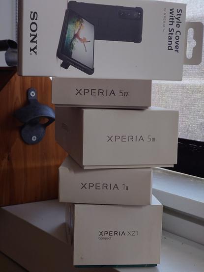 The following cellphone boxes, from bottom to top, on a white windowsill with the shade drawn to protect from the midday sun:
Xperia XZ1 Compact
Xperia 1ii
Xperia 5iii
Xperia 5iv
Sony Style Cover with Stand for Xperia 5iii