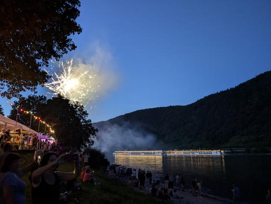 Am Rheinufer des Ortes Spay bei Koblenz.
Illuminierte Passagierschiffe passieren ein Feuerwerk.