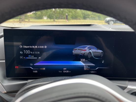 Close-up of an BMW i4 electric vehicle dashboard display showing charging progress, battery status at 83%, range of 308 km, and other driving information.
