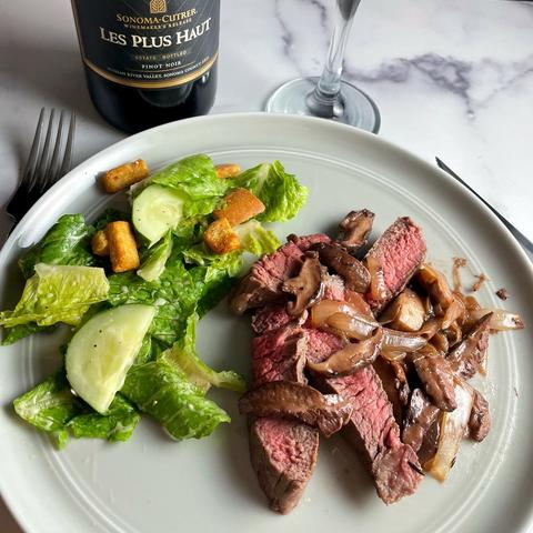 steak topped with shiitake mushrooms, served with a side green salad.