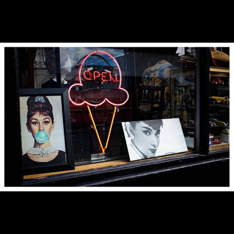Two pictures of Audrey Hepburn in an antique store front window.