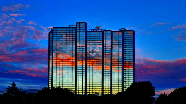 A sunset reflected in the glazed wall of a multistorey hotel.