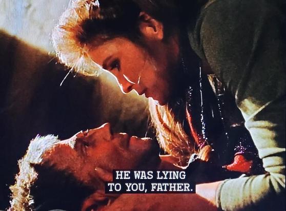 Janeway (out of uniform with hair down) holds the head of alien humanoid played by Joel Grey as he lies dying on the floor of the detention facility. He looks him in the eyes and says: He was lying to you, father.