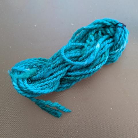 A mini skein of green tonal yarn, dyed after spinning. This is one of my long draw samples using slightly rustic Shetland and it's very unevenly spun.