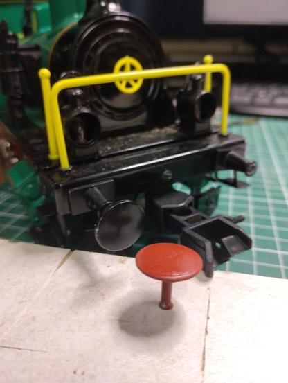 Photo of the front of a model railway steam locomotive and a brown replica buffer.
