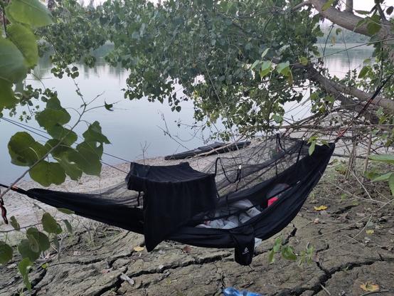 a hammok in front of a kayak in front of the po river