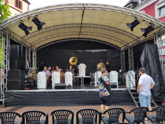 Überdachte OpenAir-Bühne, darauf
sorgsam ausgerichtete Notenpulte mit der Aufschrift KAREOL-Tanzorchester,
in der Mitte gut zu erkennen: ein Sousaphon!