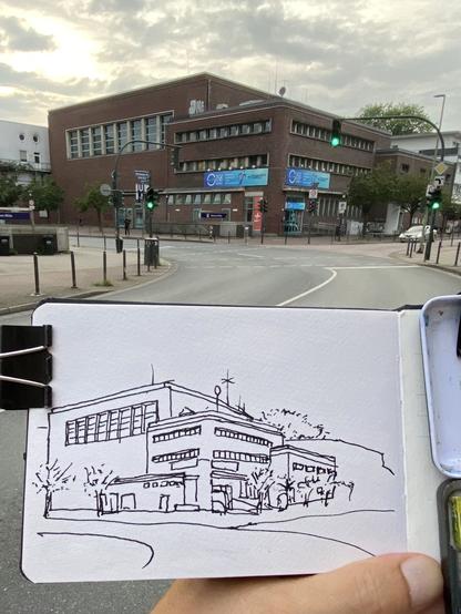 A building composed of several cubes at an intersection, with a drawing of it in the foreground.