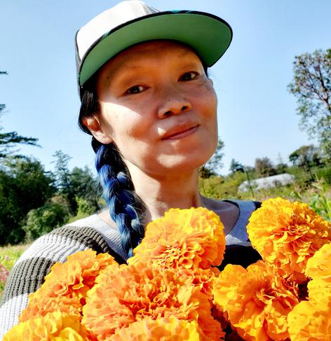 Selfie holding bucket of orange marigolds I harvested.