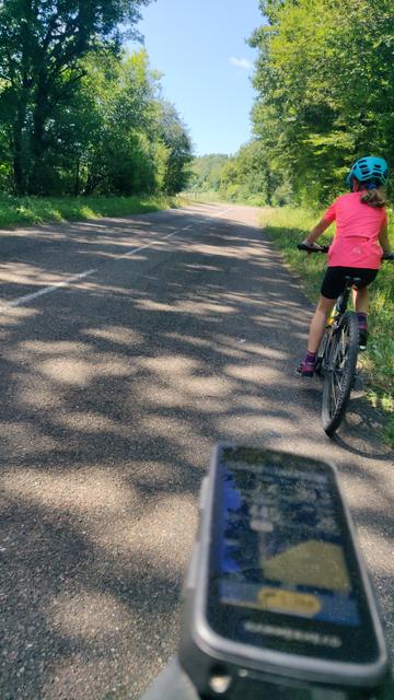 Jura-Bergsträßchen. Im Vordergrund mein Navi. Kind radelt vor mir.