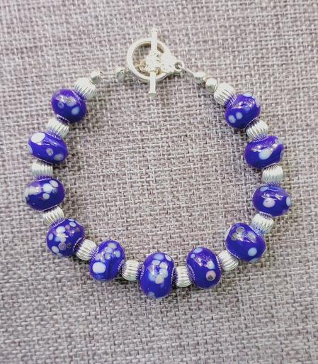 Image of a bracelet made from lampwork glass beads with added multi color frit and silver spacers.
