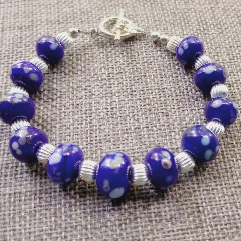 Image of a bracelet made from lampwork glass beads with added multi color frit and silver spacers.