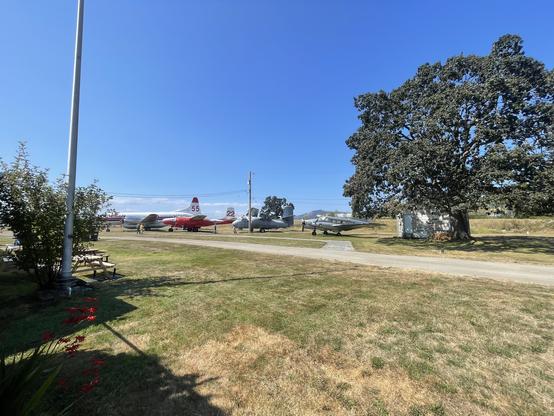 A few planes sit on a field. The furthest is a small ConAir firefighting plane, beyond that is where the HawaiiMars will be.
