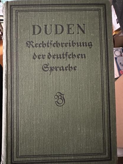 A hardcover book titled "Duden: Rechtschreibung der deutschen Sprache," featuring a green cover with black lettering and decorative borders.