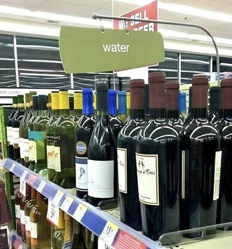 A store with shelves labeled "water" but actually full of bottles of wine