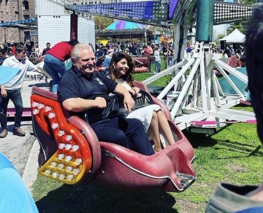 Doug Ford spinning around in a merry go round on the lawn of Queens Park