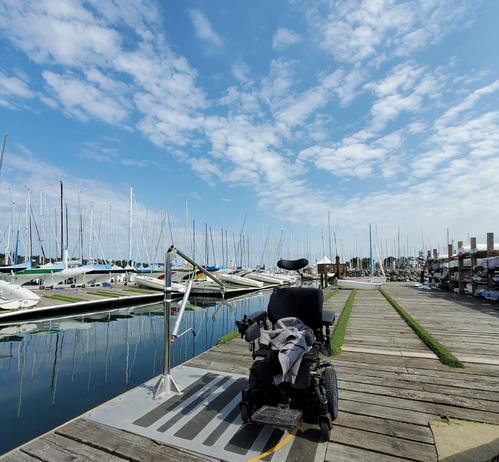 Powerchair on dock with passenger lift machine on the left of wheelchair.