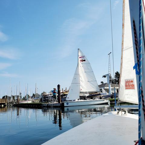View from my front pilot seat of Martin 16 sailboat, looking towards dock with identical sailboat tied up & a staff member on dock waiting for us.