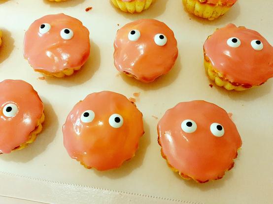 A group of round frosted pink cakes with eyes.