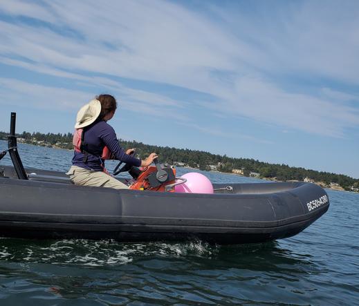 ASV in Zodiac boat with bright pink ball float marker.