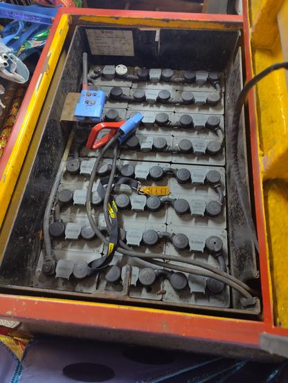 an array of very heavy looking lead acid batteries in a compartment of the tug