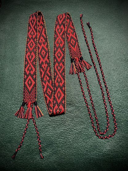 Woven band with red diamond patterns  with woven straps to attach to a lute against a green background