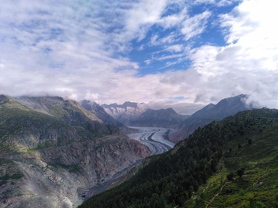 Seeing myself as a very small person among the rapidly elapsing ice of the glacier in the photo center, circled by green mountains and a blue cloudy sky