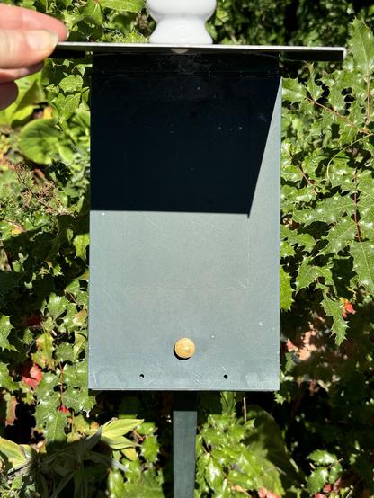 A hand is lifting the sign on the green box, showing that there is nothing posted below .