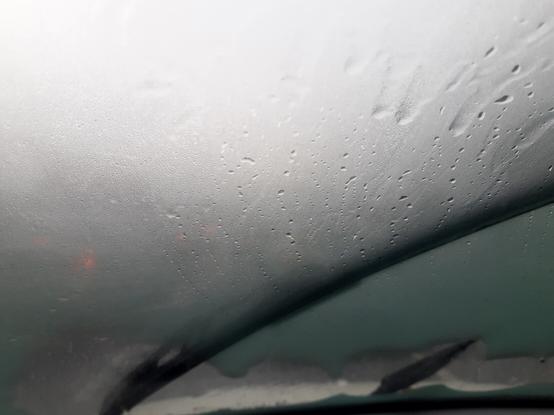 Vetro anteriore di macchina annebbiato, con tergicristalli in azione contro una violenta pioggia