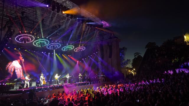 The Billy Strings concert at the Greek Theatre in Berkeley CA on Sunday, August 18, 2024. A nighttime shot of the stage structure with the band playing to the left and the attentive audience digging the scene to the right.