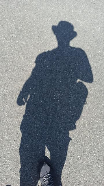 Schatten einer männlichen Person auf Asphalt.