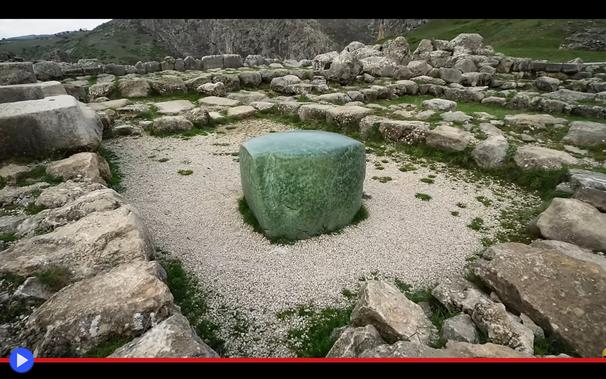 Imponente cubo di pietra verde campeggia in mezzo alle rovine di un antico tempio.
