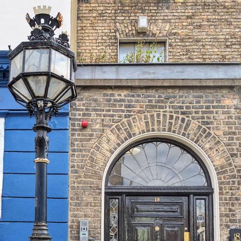 There is an ornate historic lamppost in the foreground and the top half of a black Georgian door with an ornate fanlight in the background.