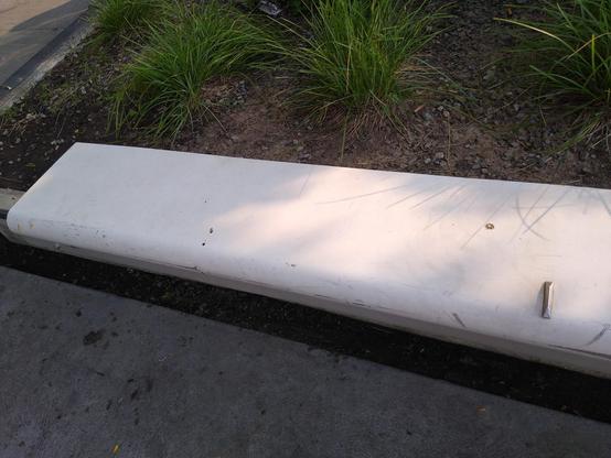 white flat bench with a visible metal spike/triangle bump protruding upward, on the lip edge of the bench