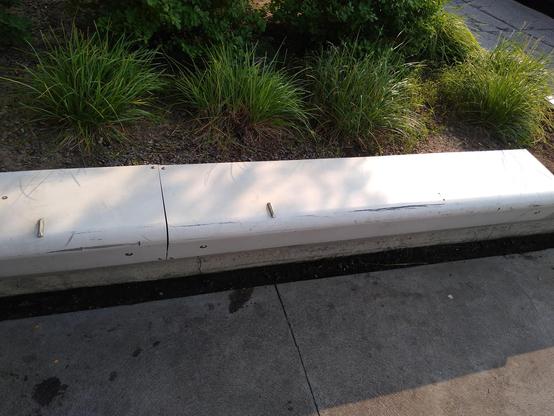white flat bench with two visible metal spike/triangle bumps protruding upward, on the lip edge of the benches