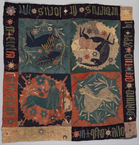 official museum photo of the textile on white background, square fragment with four inner quadrants (one for each animal) with text running along outer border, faded turquoise / vermillion / yellow / tan / green / black colors  “This textile features a combination of real and imaginary creatures. The inscription, only partially legible and apparently mixing Latin and Italian, invokes the name of Christ and the Church, indicating the cloth’s original use in a religious context.”