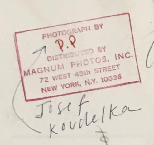 detail of stamps on back of photo:

in red rectangle, printed red text:

PHOTOGRAPH BY 
[handwritten in red ink] P.P.
DISTRIBUTED BY 
MAGNUM PHOTOS, INC.
72 WEST 45TH STREET
NEW YORK, N.Y. 10036

pencil annotation beneath reads, Josef Koudelka, and connects it with an arrow to the letters P.P. above