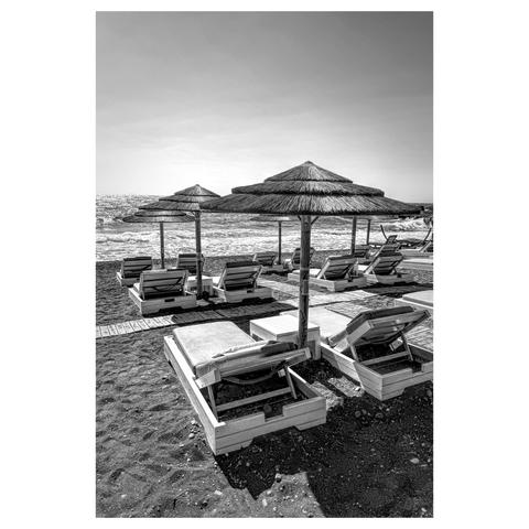 Black and white photo of Santorini beach with black sand and sunbeds