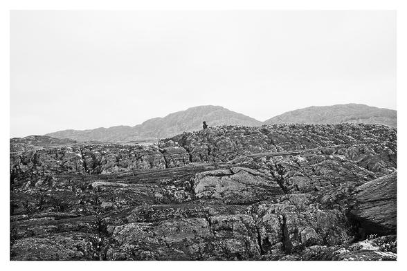 Coastal gullies and sea arches stretch into the Atlantic, my friend M is partially visible above the nearest ridge, behind her the peaks of Eagle Hills and Gortaghig stretch out east to west.